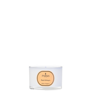 A white travel-sized candle with a label reading 'PARKS Peach & Amyris', in an elegant glass vessel.