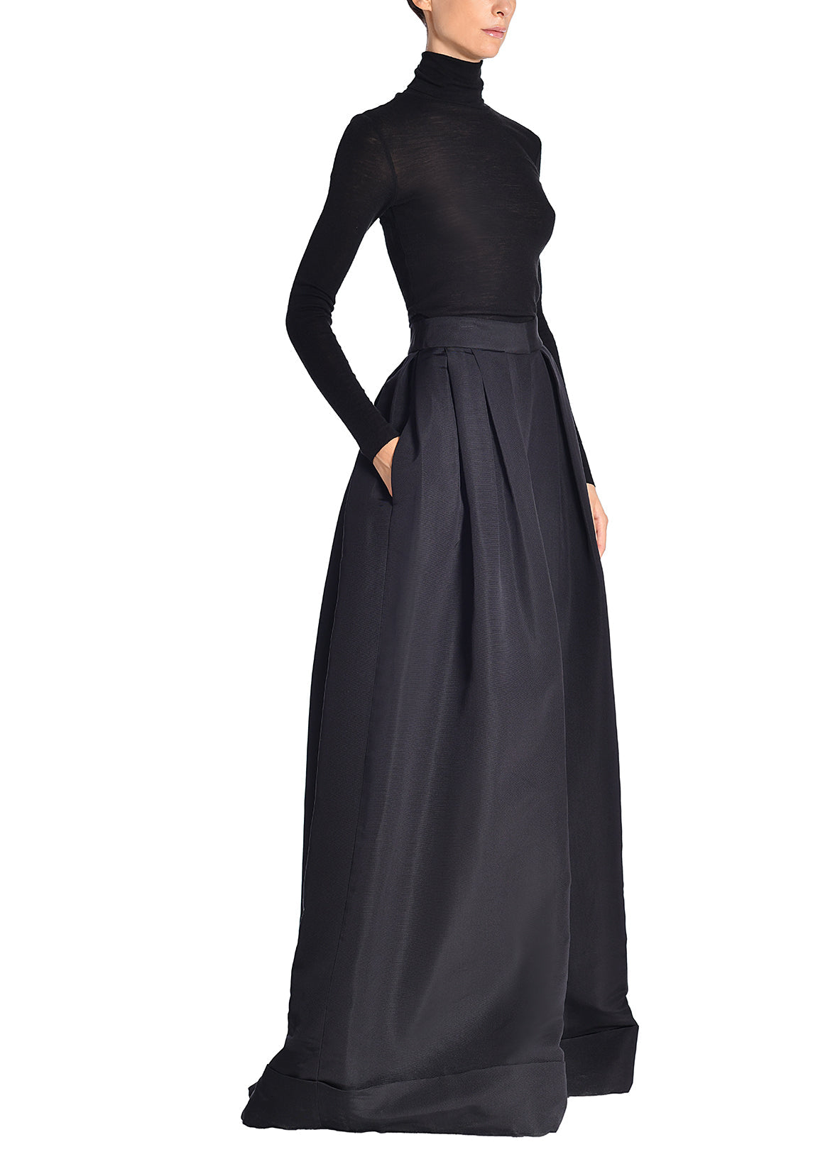 A side image of a model wearing a black turtleneck and black silk faille wide leg pants.