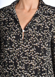 Pearl detailing at the collar of a black, floral top.