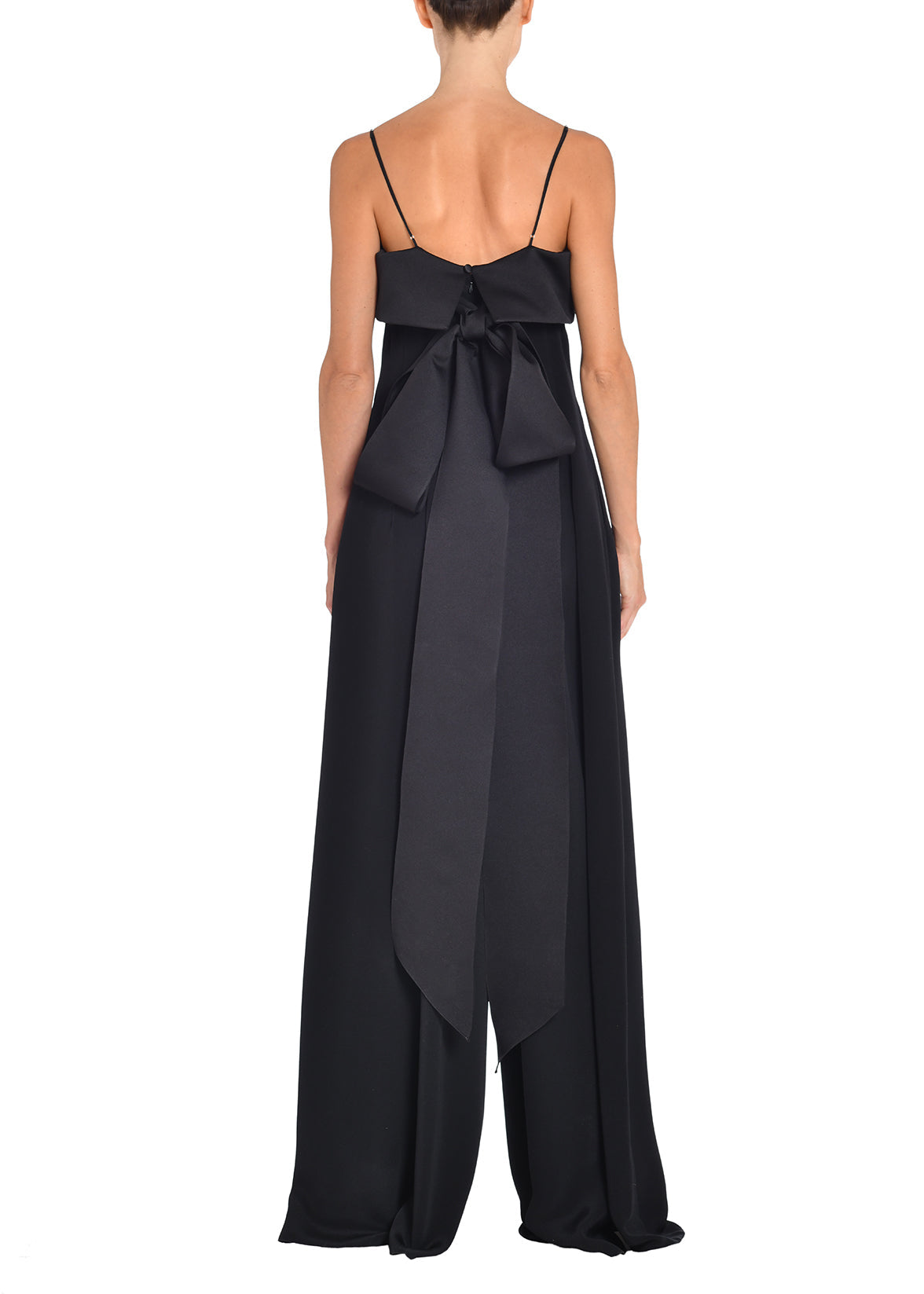 A model wearing a black silk jumpsuit with bow at the back. 