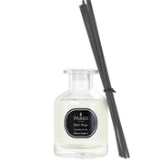 A clear glass diffuser bottle with black reeds, labeled 'PARKS Black Magic', containing a purple liquid.