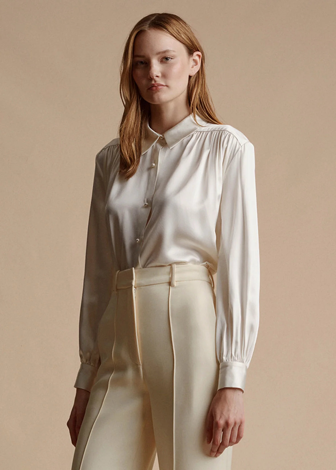 Model is wearing the ivory blouse with pearls in silk charmeuse tucked into the ivory silk wool Deeda trouser.