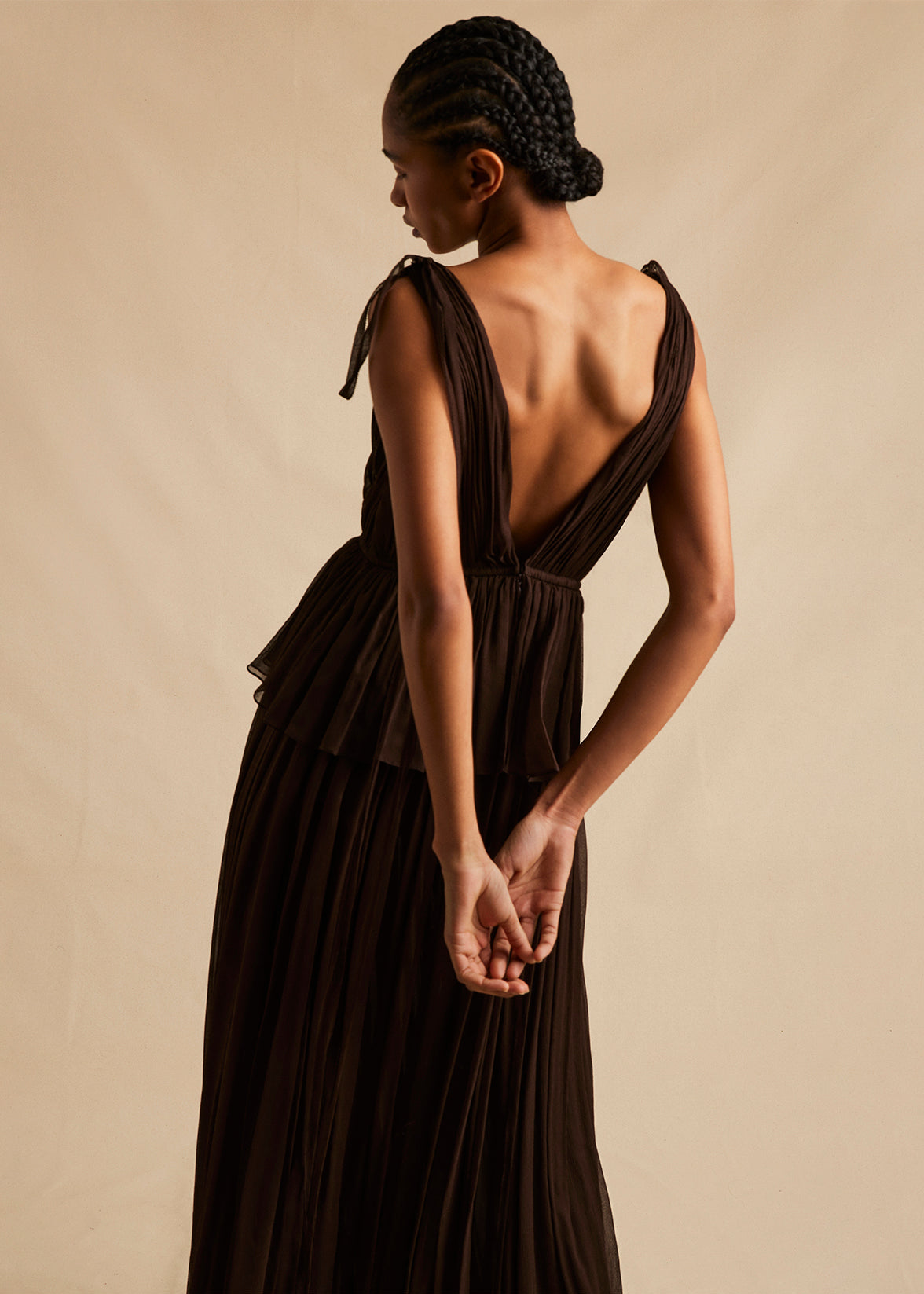 A back view campaign image of a model wearing a mocha brown silk gown. 